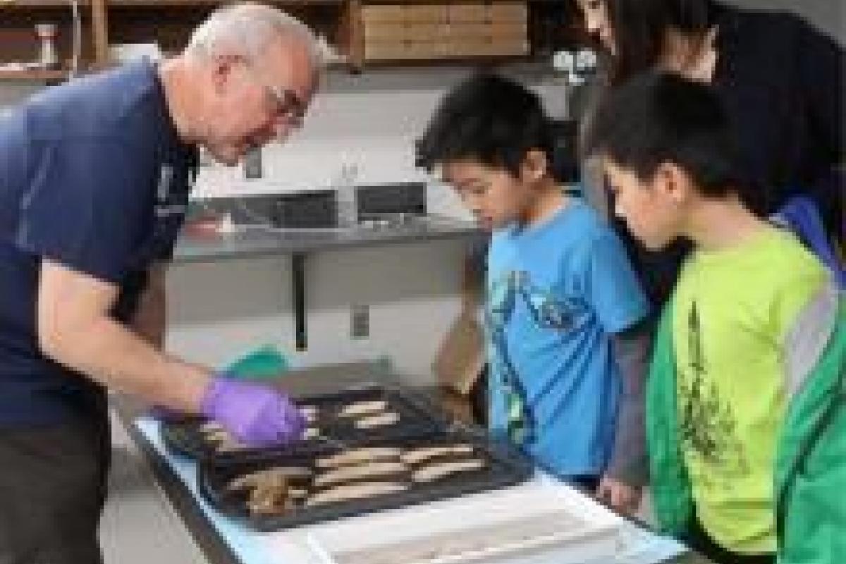 Dr. Len White, left, points out parts of the brain to young learners and their mother.