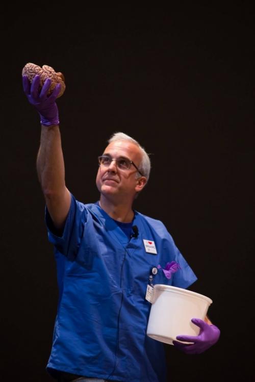 White holds a human brain aloft during a Duke School of Medicine Student Faculty Show.